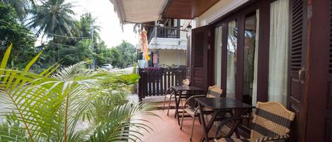 A terrace with a table and chairs, surrounded by lush greenery and a view of palm trees.