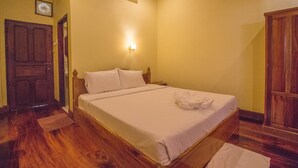 A bedroom with a wooden bed, a nightstand, an air conditioning unit, and a wooden wardrobe. - Villa Somphong (Luang Prabang)