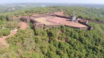 An ancient fort with a large courtyard and a prominent tower, surrounded by dense forest.