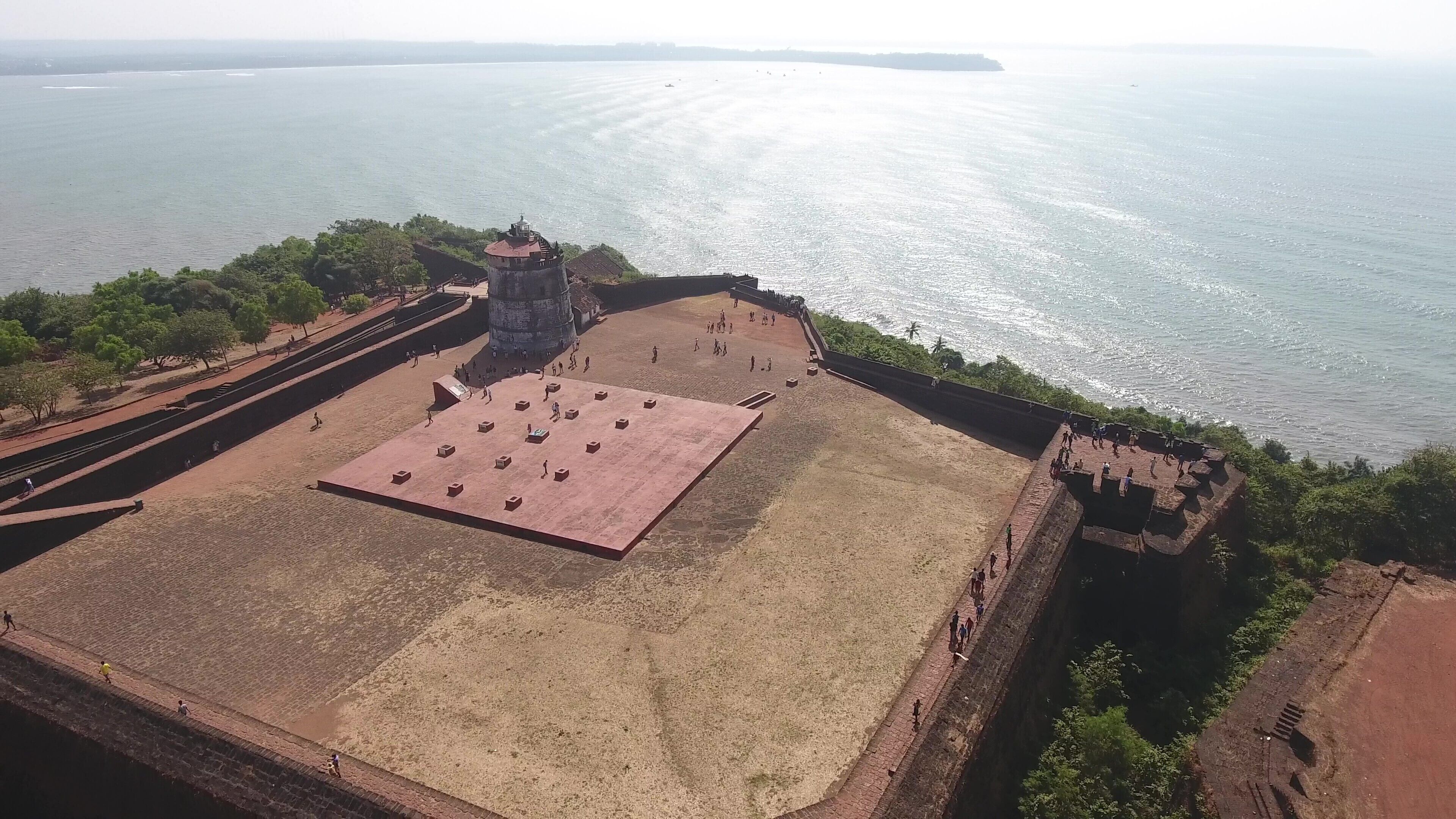 An aerial view of a historical fort with a large open courtyard, a watchtower, and a surrounding wall.