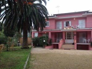 A pink building with a sign reading "Hotel Villa Rosa".