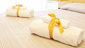 Ein Hotelzimmer mit einem Bett, einem Nachttisch und zwei Handtüchern mit gelben Bändern.