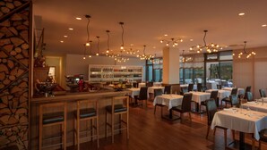 A restaurant with multiple tables and chairs, a bar area, and a large window offering a view of the outdoors. - Dioklecijan Hotel & Residence (Split)
