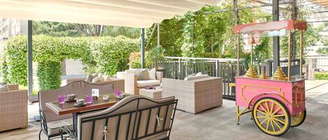 An outdoor seating area with wicker furniture and a pink cart.