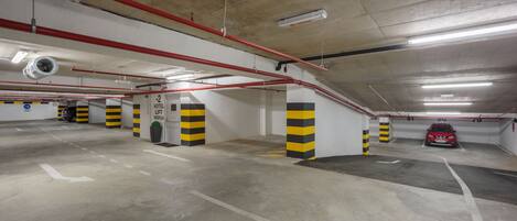 A multi-level parking garage with clearly marked parking spaces, a lift reception area, and visible structural elements like beams and columns.