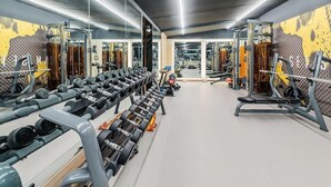 Ett gym med spegelbeklädda väggar, ställningar för vikter och träningsutrustning.