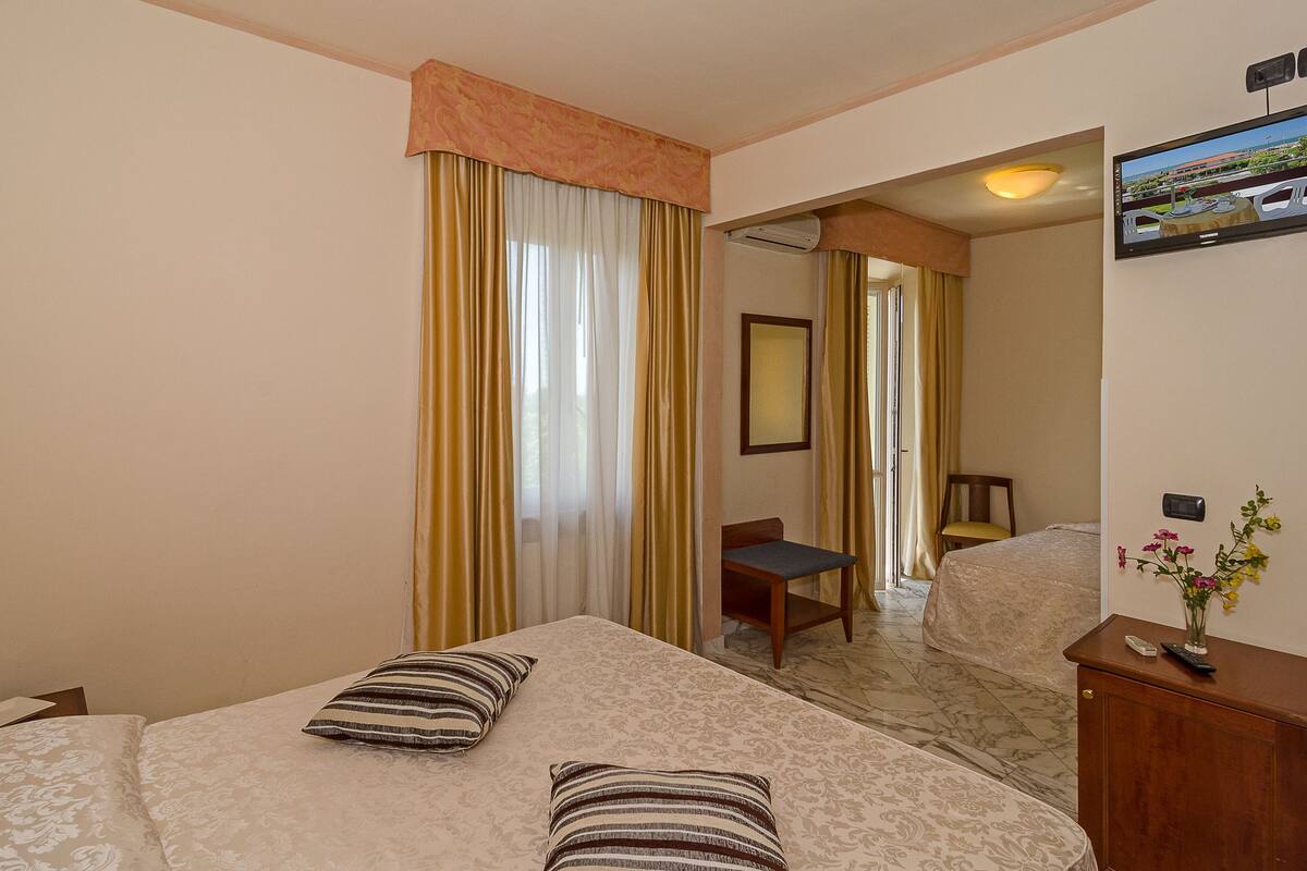 A hotel room with a bed, a desk, a chair, and a television.