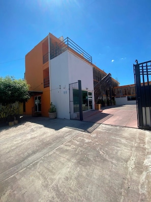 A building with a flat roof, a gated entrance, and a concrete courtyard. - Maxihotel Los Mochis (Los Mochis)