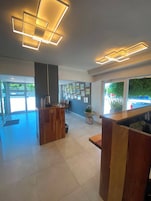 Un hall espacioso con una mesa de recepción, una pared decorada con cuadros enmarcados y un gran ventanal con vistas al exterior.