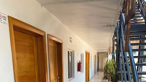 Un pasillo de hotel con puertas de madera, un extintor y plantas en macetas.