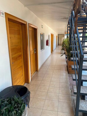 A hotel corridor with wooden doors, a fire extinguisher, and potted plants. - Maxihotel Los Mochis (Los Mochis)