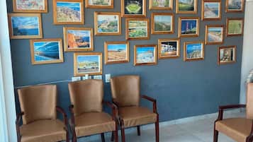 Ein Zimmer mit einer Wand voller gerahmter Landschaftsbilder, Ledersesseln und runden Holztischen.