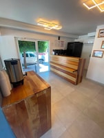 Una zona de recepción con un mostrador de madera, un basurero y un refrigerador al fondo.