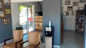 Vestíbulo de hotel con dos sillones de cuero, un dispensador de agua y un mostrador de recepción.