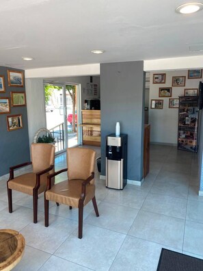 A hotel lobby with two leather chairs, a water dispenser, and a reception desk. - Maxihotel Los Mochis (Los Mochis)