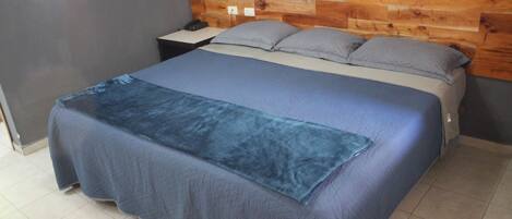 Quarto com uma cama, mesa de cabeceira e cabeceira de madeira.