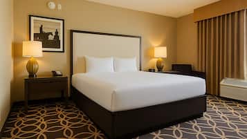 A hotel room with a large bed, two bedside tables with lamps, a framed picture on the wall, and a patterned carpet.