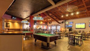 A spacious indoor area with a pool table, multiple tables and chairs, and a bar area. - Zia Park Hotel (Hobbs)