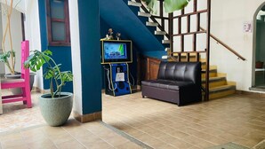 Una sala de estar con un sofá, televisor, una escalera y una planta en maceta.