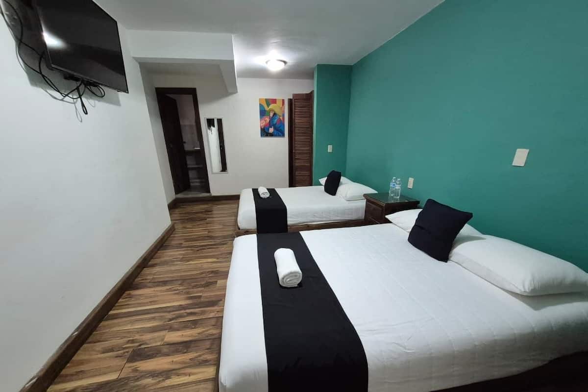 A hotel room with two beds, a TV, a painting, and a wooden floor.