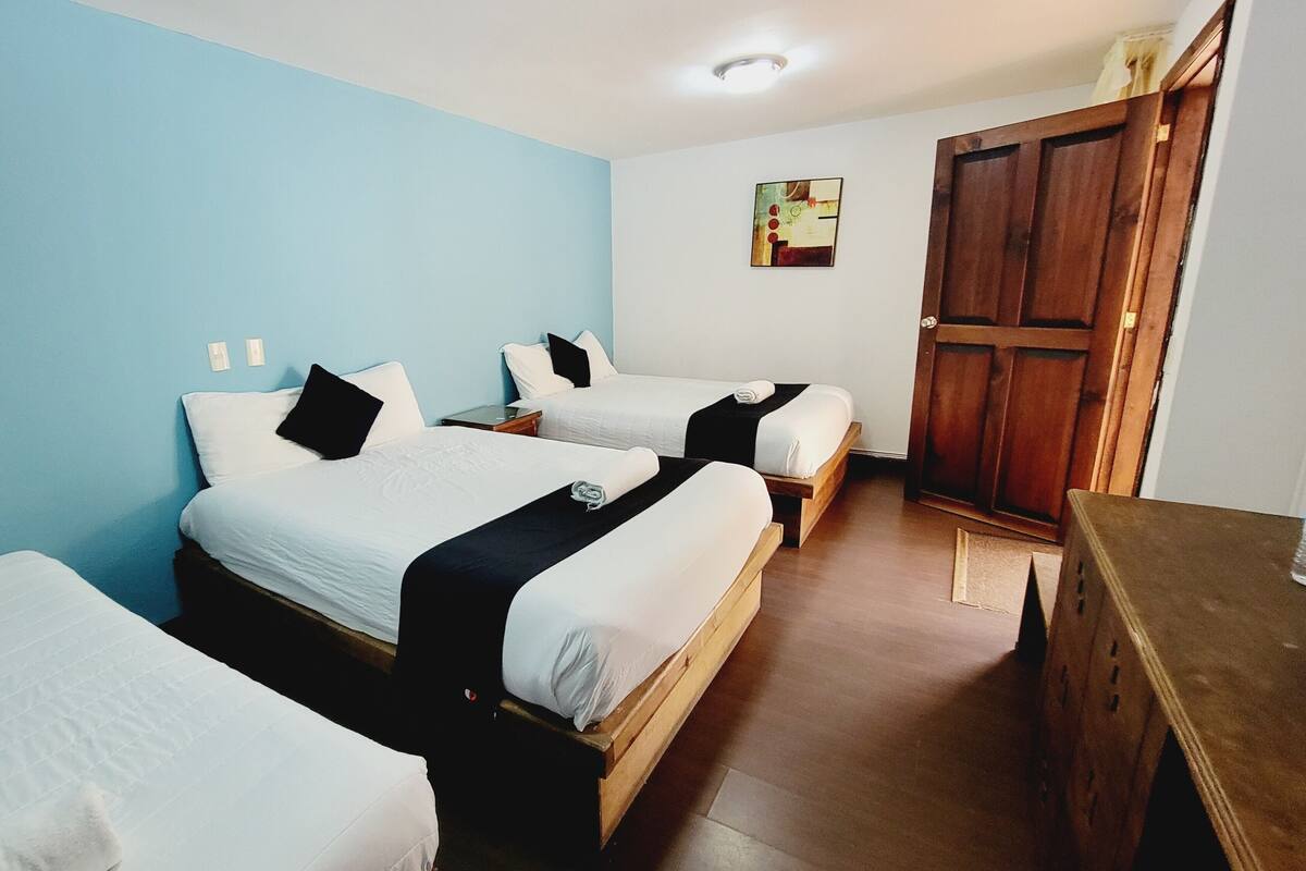 A hotel room with two beds, a wooden wardrobe, and a small desk.