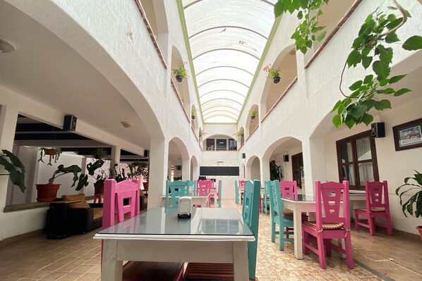 A spacious indoor area with a high ceiling, multiple seating arrangements, and potted plants. - Jardines de Luz (San Cristóbal de las Casas)