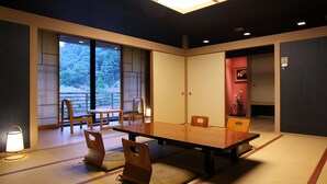 A traditional Japanese-style room with tatami flooring, a low table, and wooden chairs. - Minamitei (Izumisano)