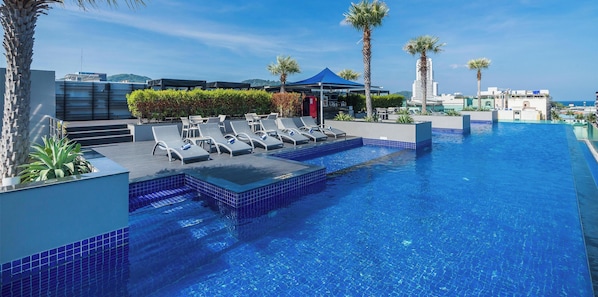 A rooftop pool with lounge chairs, palm trees, and a view of the city. - Best Western Patong Beach (Patong)