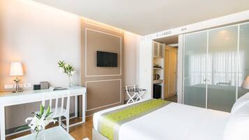 A hotel room with a bed, a desk with a lamp, a TV, and a sliding door to a bathroom.