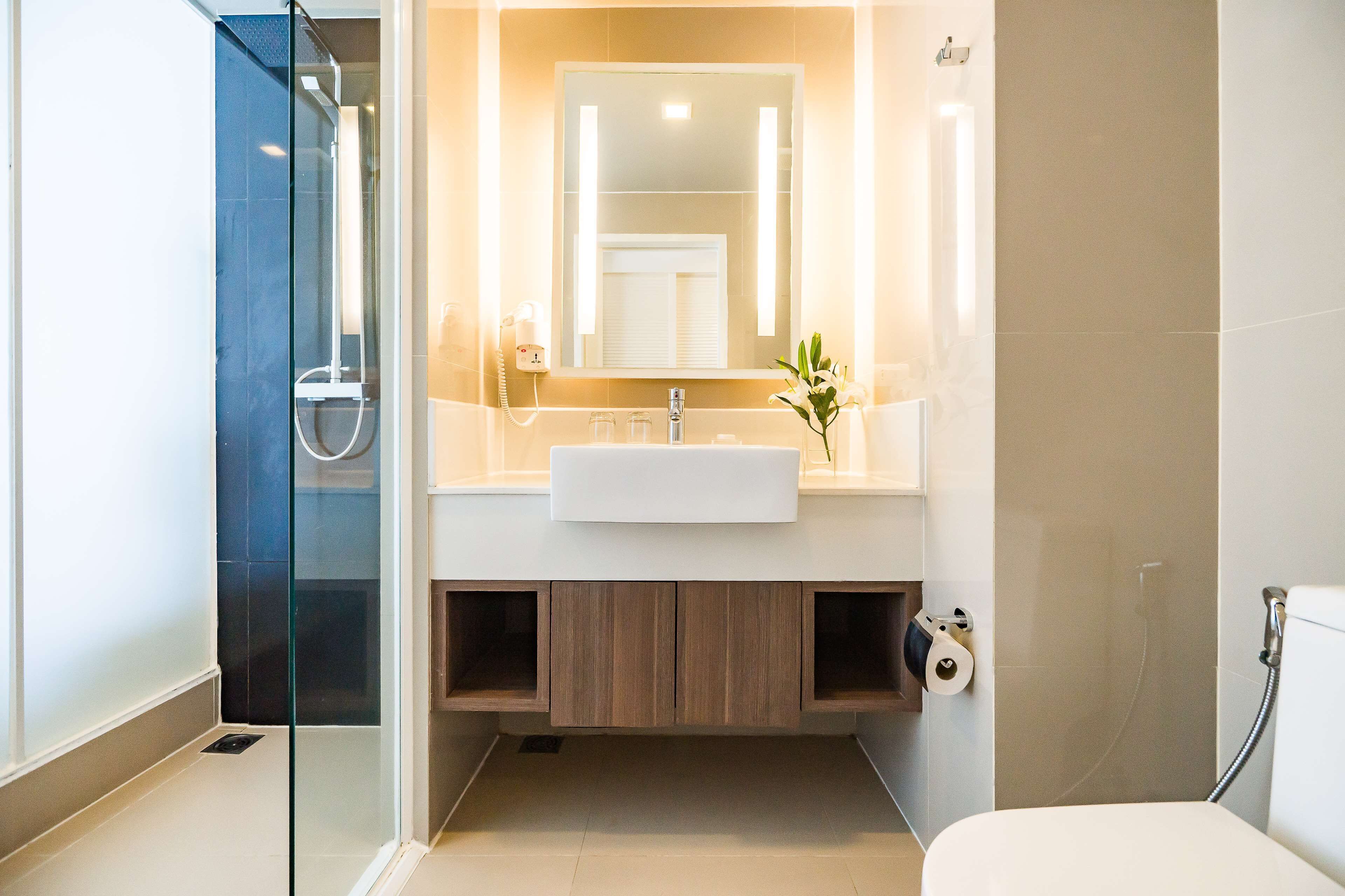 A modern bathroom with a glass shower enclosure, a white sink, and a mirror above it.
