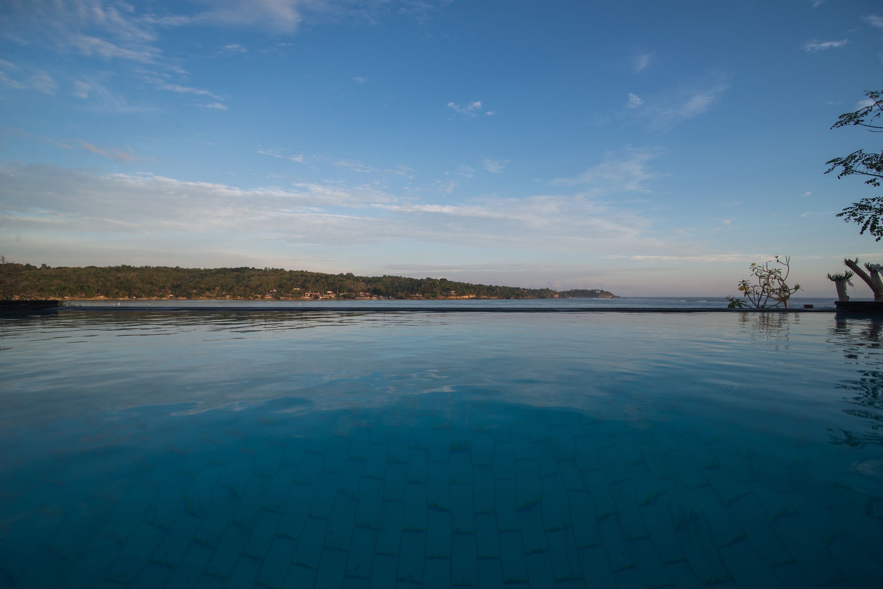 Piscina de blau clar amb vista a la riba llunyana i arbres.