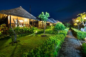 A row of thatched-roof cottages with a paved pathway and lush greenery. - Laguna Reef Huts (Lembongan Island)