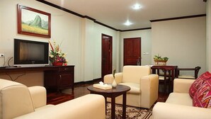 A living room with a flat-screen TV, two sofas, a coffee table, and a painting on the wall. - Vansana Riverside Hotel (Vientiane)