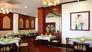 A restaurant with wooden paneling, green tablecloths, and a framed picture on the wall. - Vansana Riverside Hotel (Vientiane)