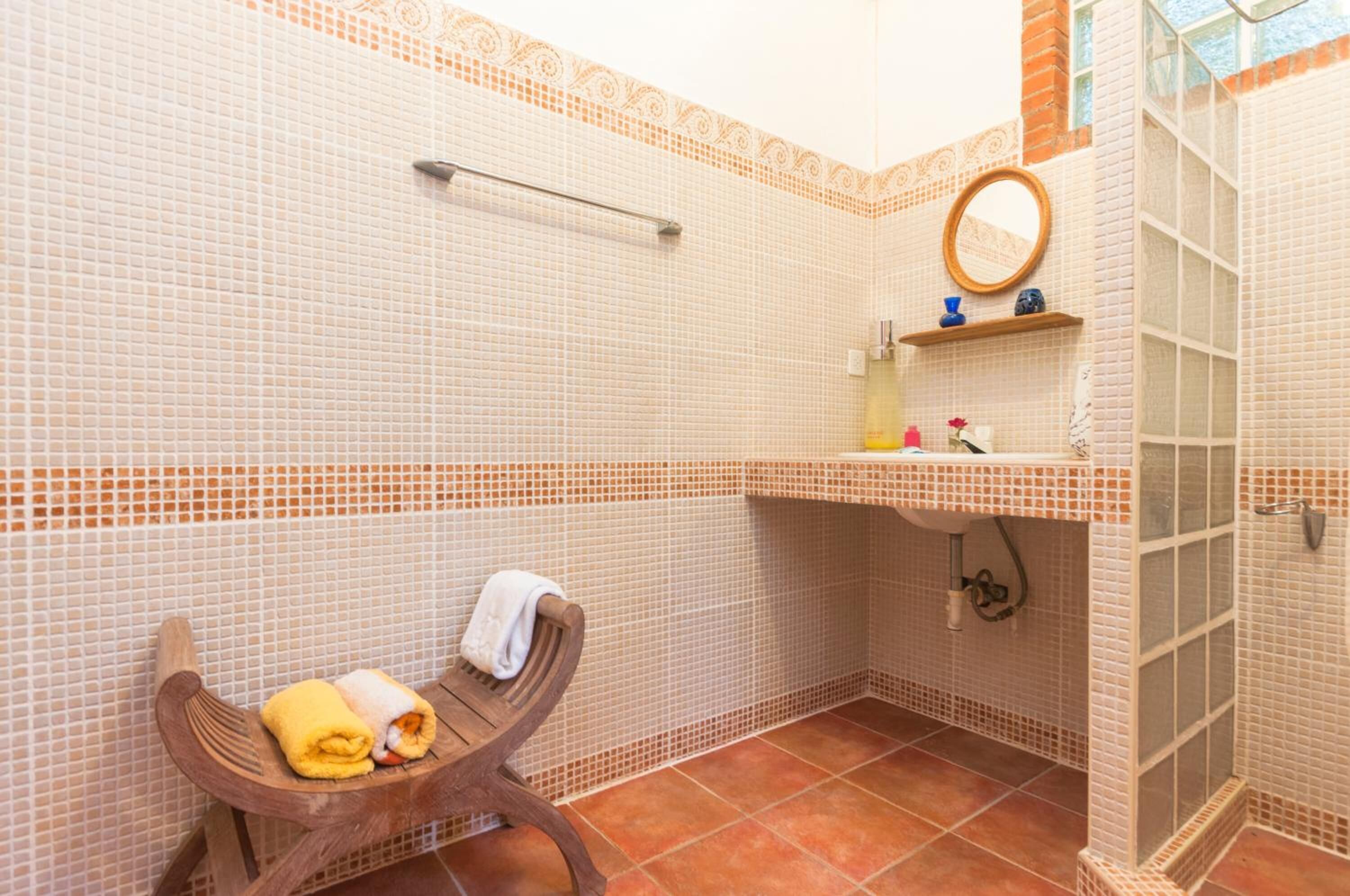 A bathroom with a shower, a sink, a mirror, and a towel rack.