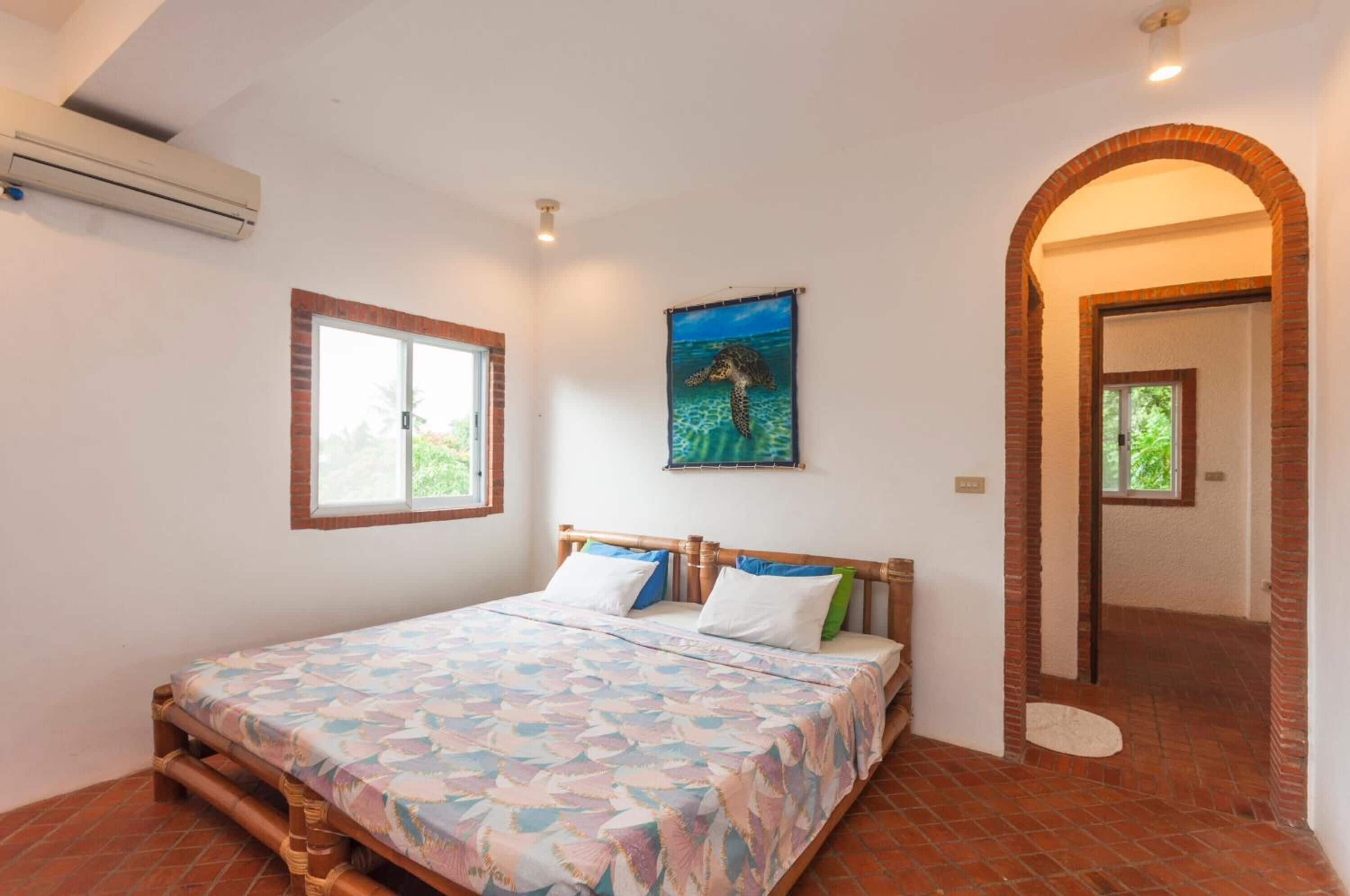 A bedroom with a bed, a window, and a door.