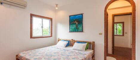 A bedroom with a bed, a window, and a door.