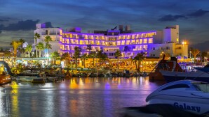A multi-story hotel with balconies, a marina with boats, and a waterfront view. - Limanaki Beach Hotel (Ayia Napa)