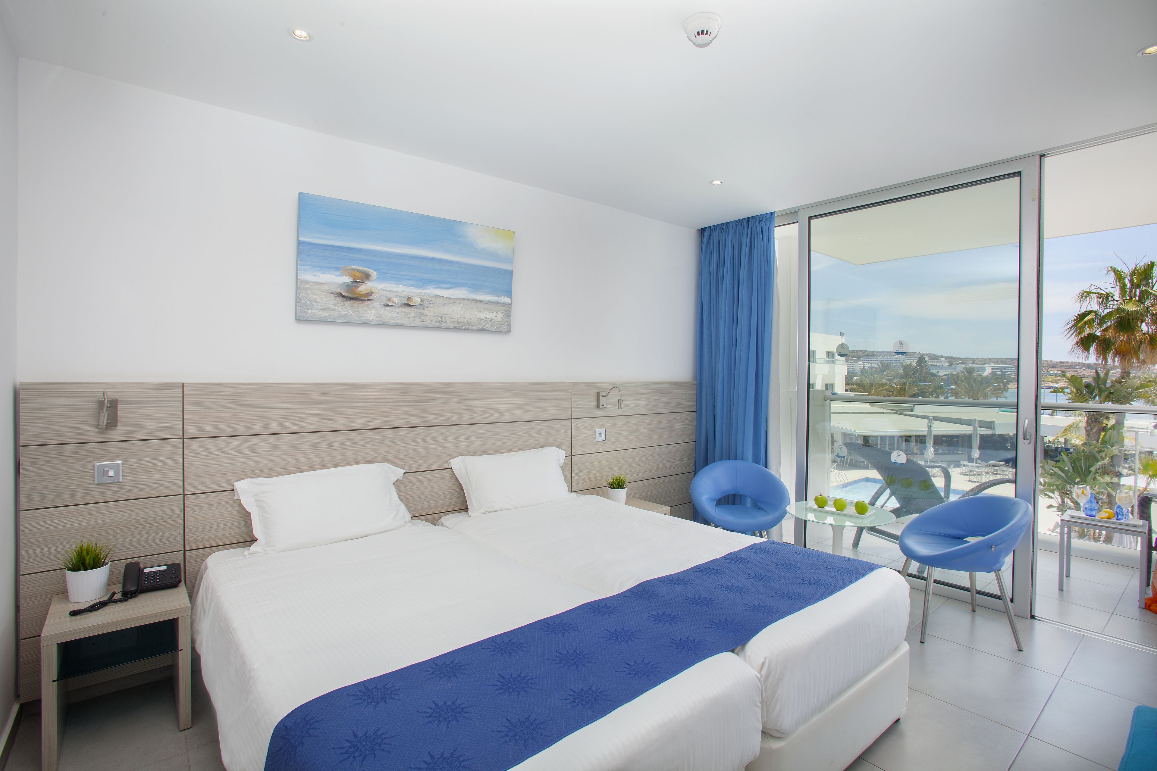 Una camera d'albergo moderna con un letto grande, una scrivania, una sedia e un balcone con vista.