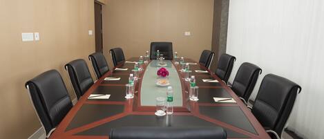 A conference room with a long table, black leather chairs, and water bottles.