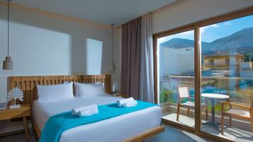 Ein Hotelzimmer mit einem großen Bett, einem Holzkopfteil, einem Balkon mit Stühlen und Blick auf die Berge.