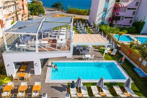 Una piscina al aire libre de temporada, sombrillas, tumbonas