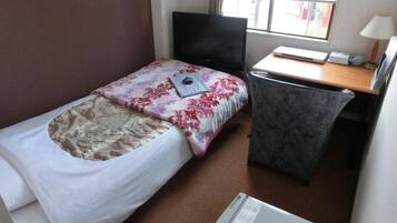 Una habitación de hotel pequeña con una cama individual, un escritorio, una silla, un televisor y una ventana.