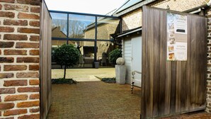 A brick building with a glass door entrance, a wooden door, and a signboard. - Hotel de Maretak (Dilsen-Stokkem)