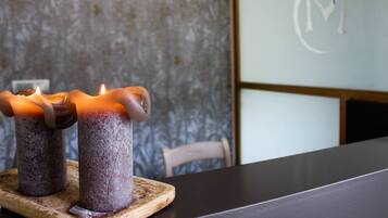 Two candles on a wooden coaster on a table.