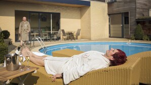 A person relaxing on a wicker lounge chair by a pool, with a bucket of champagne and glasses on a table. - Hotel de Maretak (Dilsen-Stokkem)