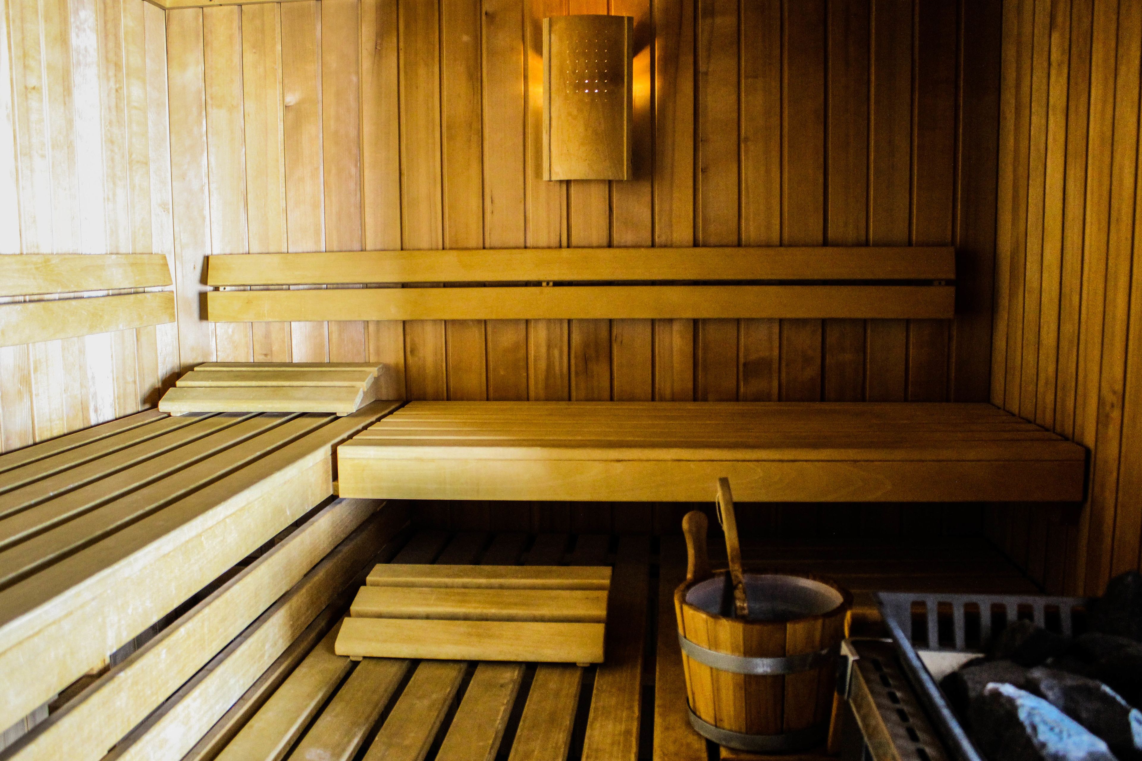 A wooden sauna with benches and a wooden bucket with a ladle.
