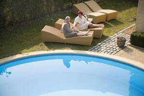 A poolside area with lounge chairs and a potted plant.