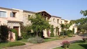 A stone building with a tiled roof, a paved driveway, and well-maintained landscaping. - Il Borgo Appartamenti by Kasavacanze (Loiri Porto San Paolo)