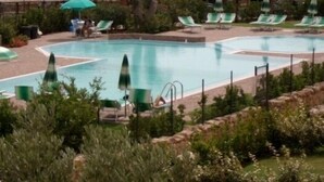 A swimming pool with multiple lanes, surrounded by green umbrellas and lounge chairs. - Il Borgo Appartamenti by Kasavacanze (Loiri Porto San Paolo)